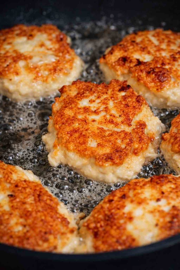 Goldbraun gebratene Hähnchenpuffer aus dem Thermomix in einer Pfanne.